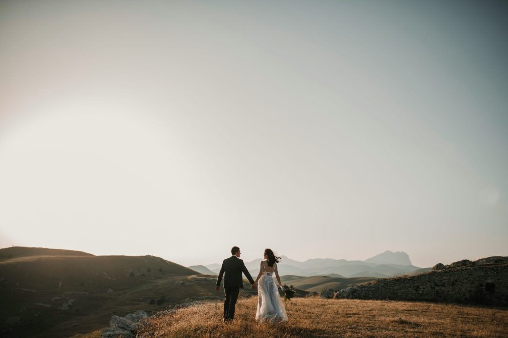 Una novia y un novio caminando por una colina